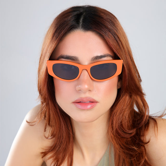 Model with red hair in an olive blouse wearing Alexa Sunglasses Aperol with Grey Flat