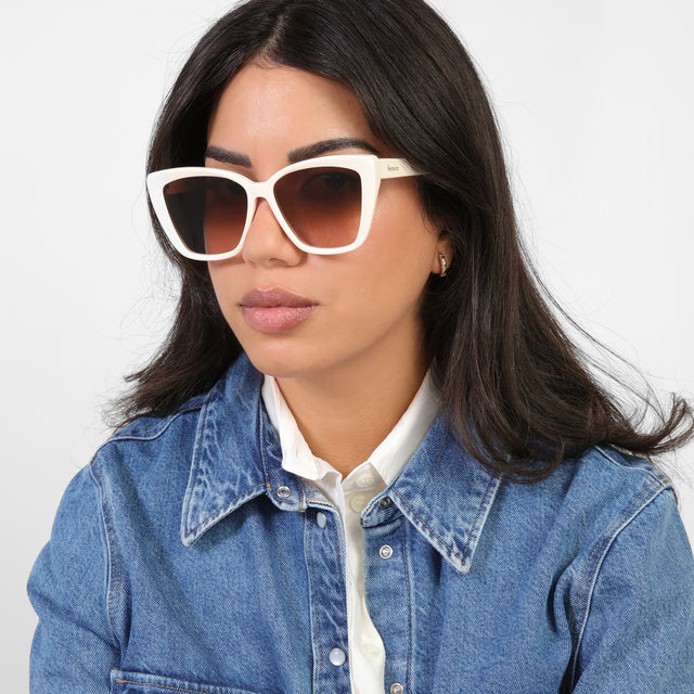 Brunette model in a denim jacket looking right wearing Barcelona Sunglasses Cream with Brown Flat Gradient