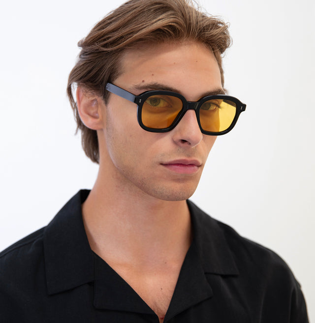 Model with semi short brown hair wearing Bogota Sunglasses Black with Honey Flat See Through