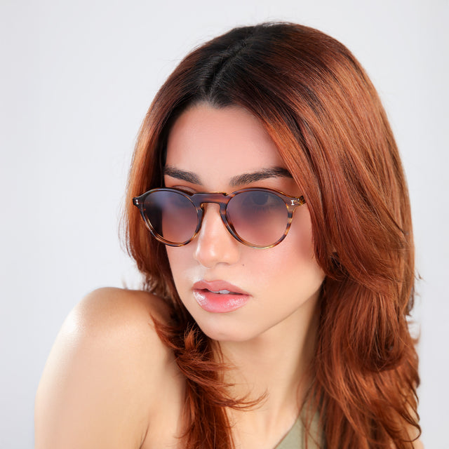 Another angle of woman with red hair in an olive blouse, looking right wearing Capri Sunglasses Sand Dune with Brown Gradient