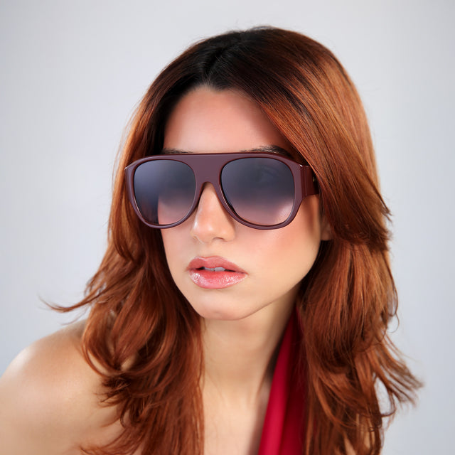 Woman with red hair in a red one-shoulder blouse wearing Colorado Sunglasses Bordeaux with Grey Gradient