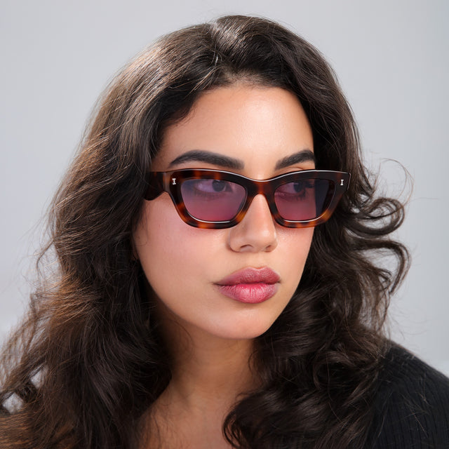 Woman with curled, brown hair looking left wearing Donna Sunglasses Havana with Plum See Through