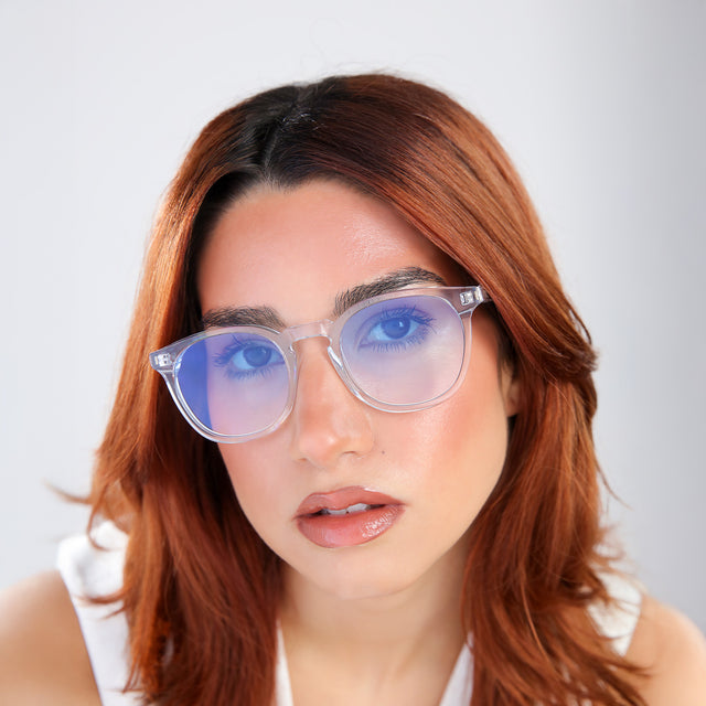 Close up of woman with red hair in a white blouse wearing Eldridge Sunglasses Clear with Blue Flat Gradient See Through