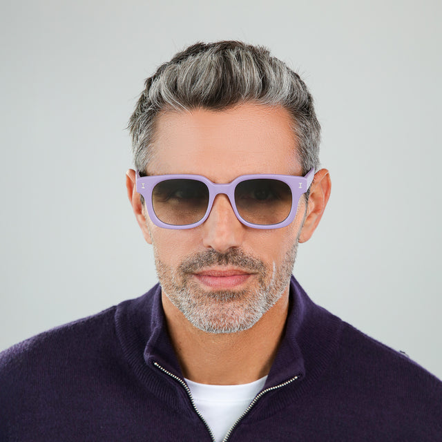 Model with salt and pepper hair and beard in a dark plum half-zip wearing Ellison Sunglasses Matte Lavender with Olive Flat Gradient