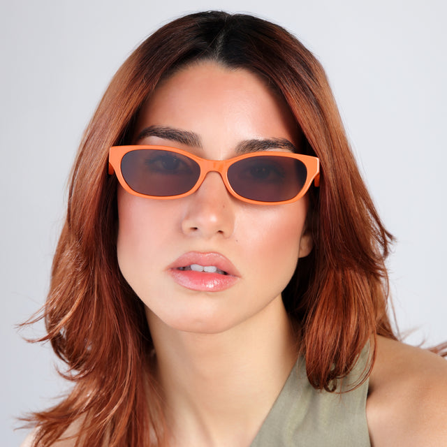 Woman with red hair in a green mockneck blouse wearing Encinitas Sunglasses Aperol with Brown