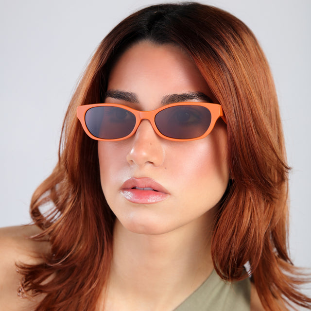 Another angle of woman with red hair in a green mockneck blouse wearing Encinitas Sunglasses Aperol with Brown