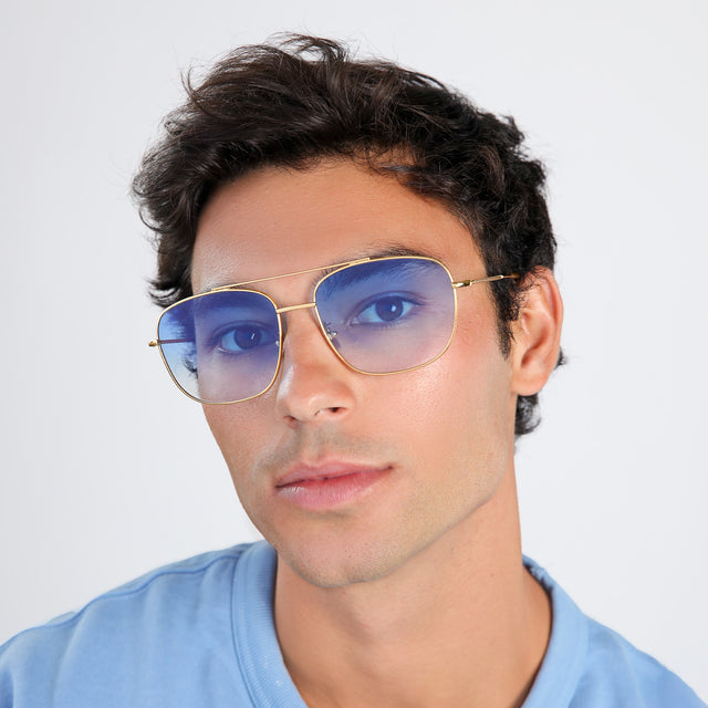 Man with brown hair in a light blue shirt wearing Frankie Sunglasses Gold with Blue Flat Gradient See Through