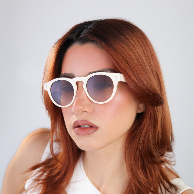 Woman with red hair in a white blouse wearing Leonard Sunglasses Cream with Brown Gradient