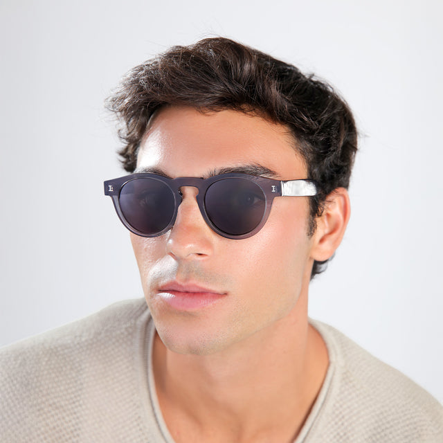 Man with brown hair in a beige waffled sweatshirt wearing Leonard Sunglasses Mercury with Grey