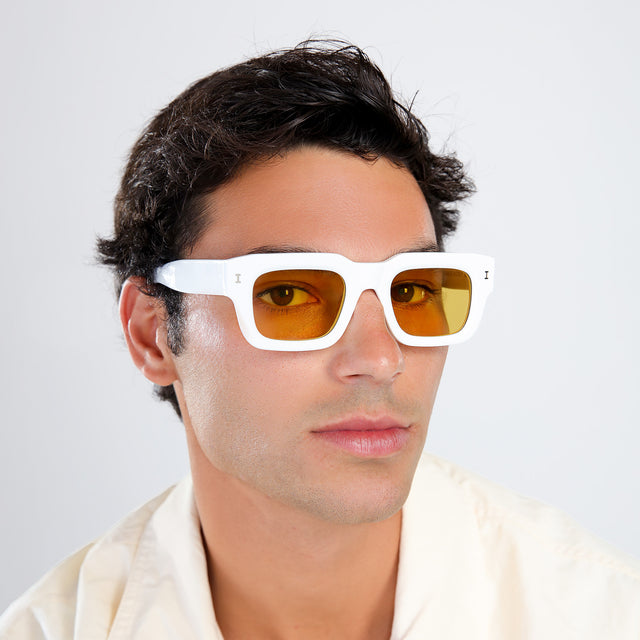 Man in a pastel linen shirt looking right wearing Lewis 50 Sunglasses White with Honey Flat See Through