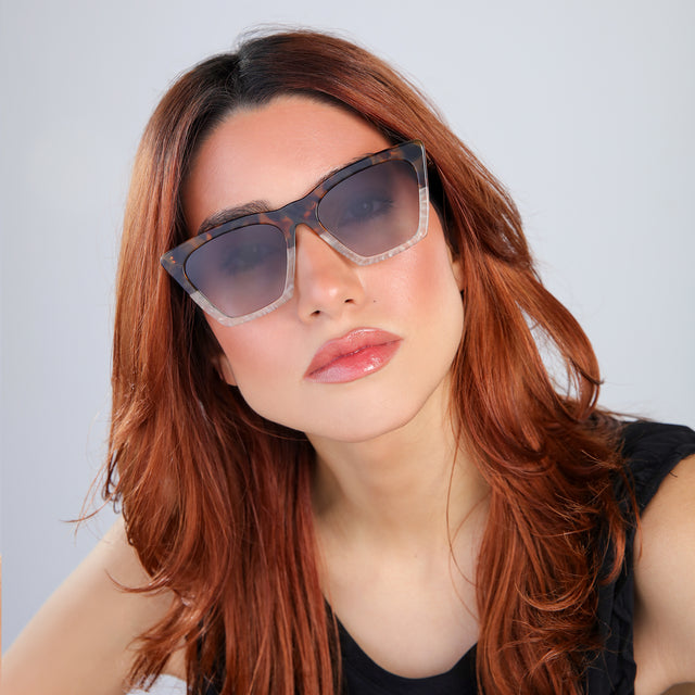Woman with red hair in a black blouse Lisbon Sunglasses side view in H/H Maple Bone / Grey Gradient