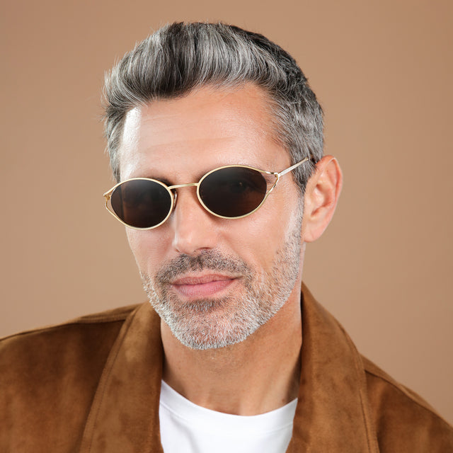 Man in a suede jacket wearing Maria Sunglasses Gold with Brown