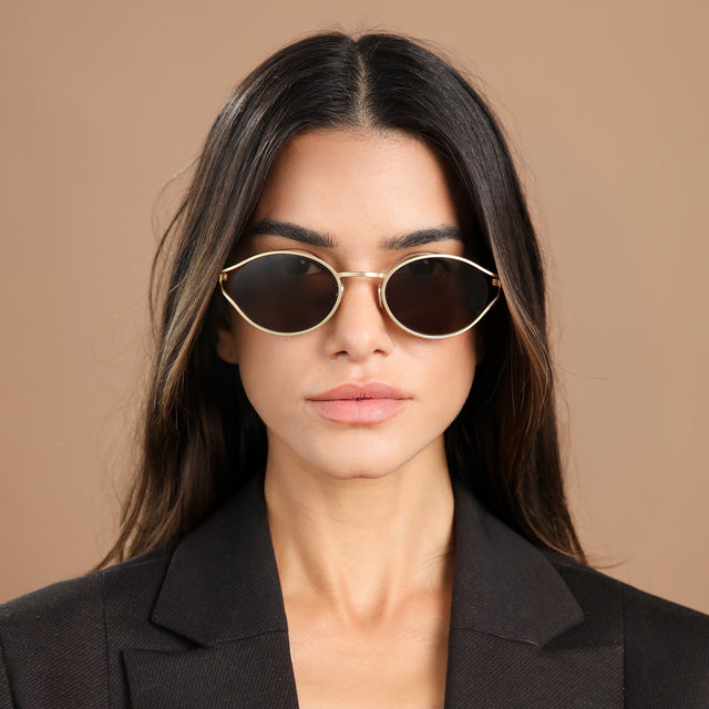 Brunette model in a black blazer wearing Maria Sunglasses Gold with Brown