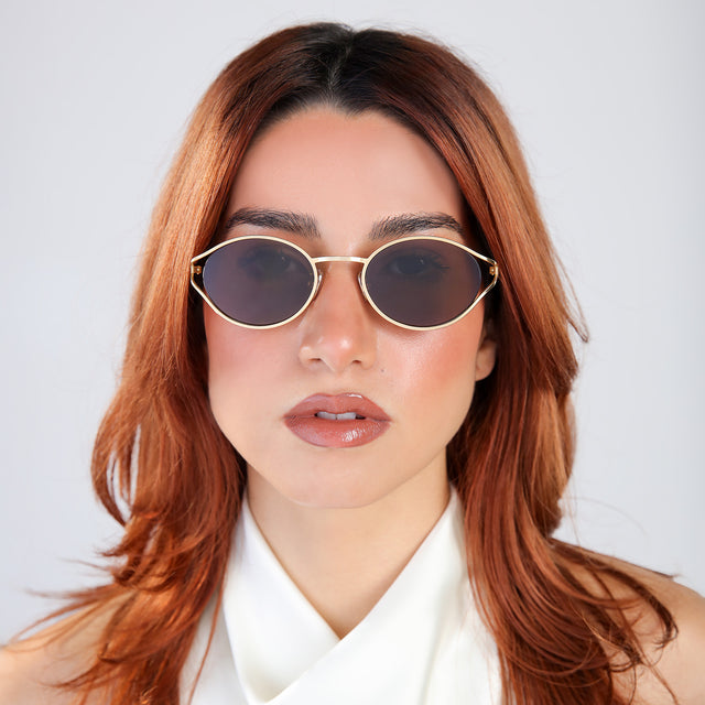 Woman with red hair in a white blouse wearing Maria Sunglasses Gold with Brown