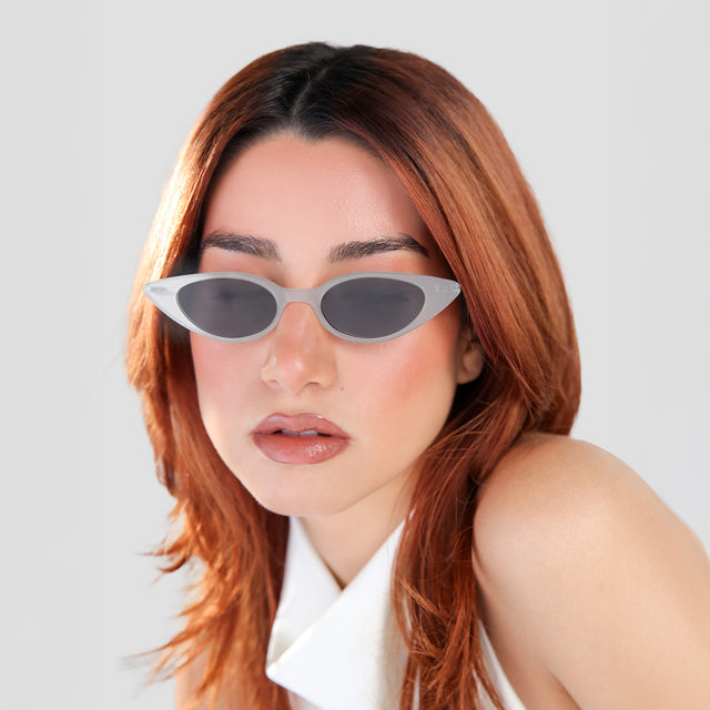 Woman with red hair in a white blouse wearing Marianne Sunglasses Powder/Gunmetal with Grey Flat