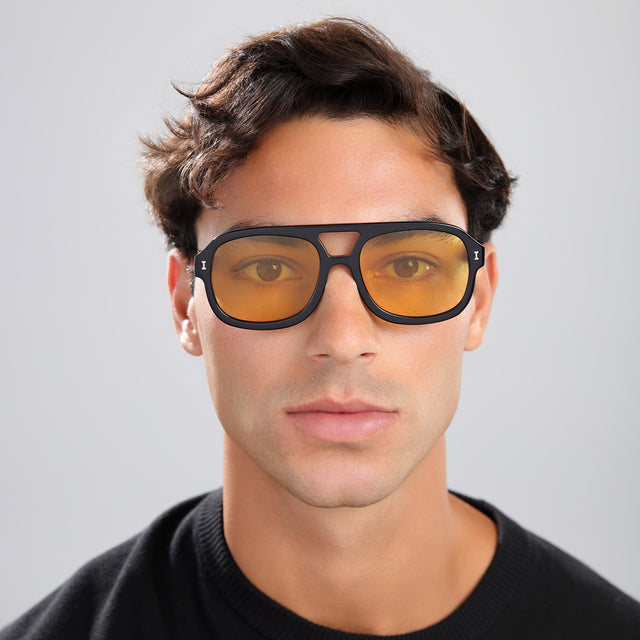 Man with brown hair in a black tee wearing Memphis Sunglasses Black with Honey See Through