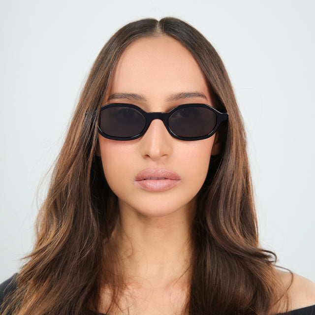 Brunette woman in an off-the-shoulder blouse wearing Munich Sunglasses Black with Grey Flat