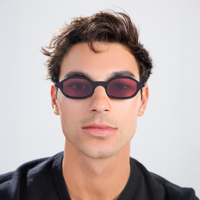 Man with brown hair in a black shirt wearing Munich Sunglasses Black with Plum Flat See Through