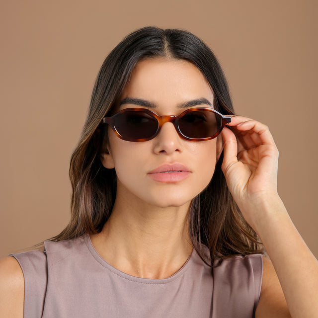 Brunette model in a lavender mockneck blouse wearing Munich Sunglasses Havana with Grey Flat