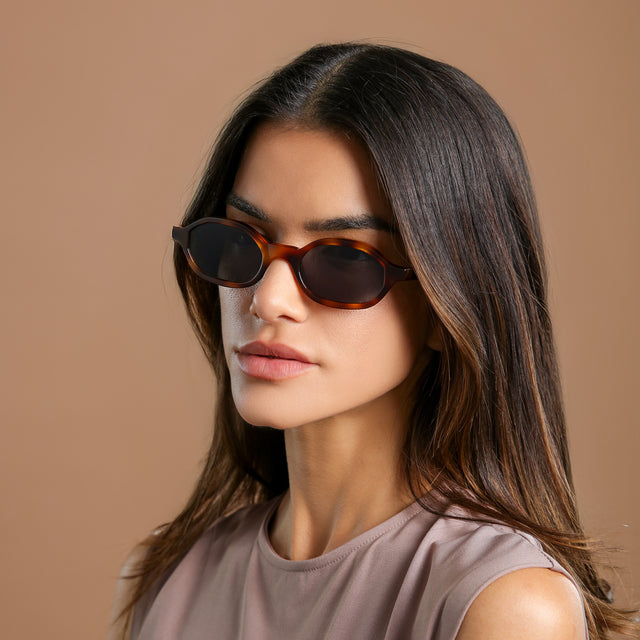 Brunette model in a lavender mockneck blouse glancing left wearing Munich Sunglasses Havana with Grey Flat