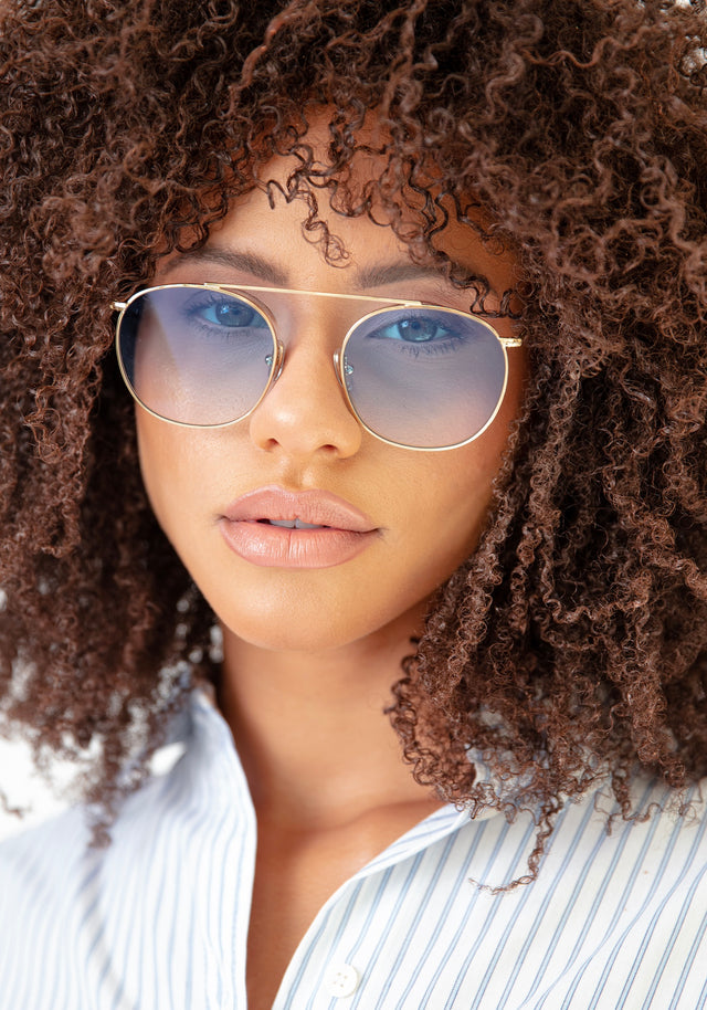 Brunette model with tight, natural curls wearing Mykonos II in Gold with Blue Gradient See Through