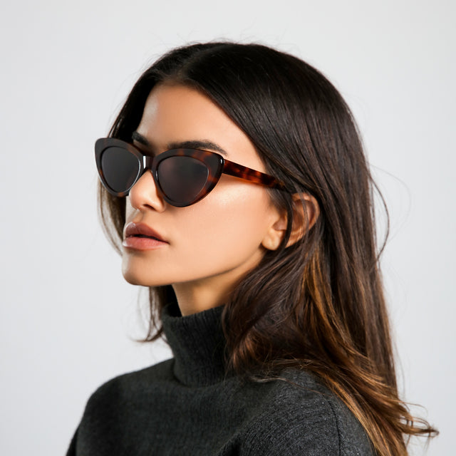 Angled shot of brunette model in a heather grey cashmere turtleneck looking forward wearing Pamela Sunglasses Havana with Grey Flat