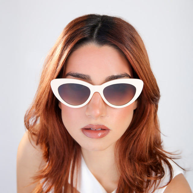 Woman with red hair in a white blouse wearing Pamela Sunglasses Cream with Brown Flat Gradient