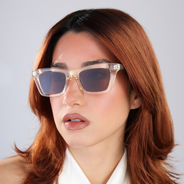 Another angle of woman with red hair in a white blouse wearing Portugal Sunglasses Champagne with Brown Flat