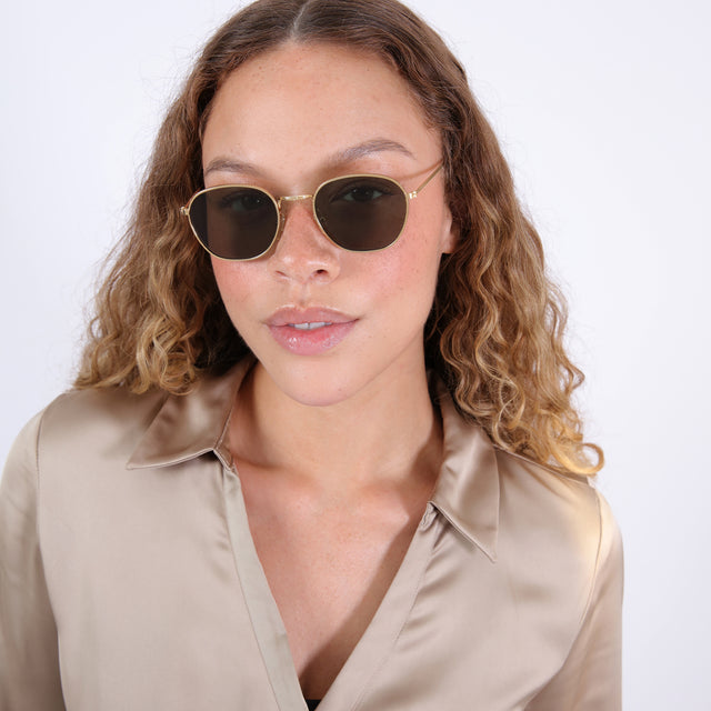 Brunette model with ombré, natural curls wearing Prince Sunglasses Gold with Olive Flat