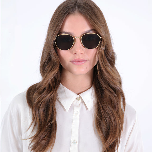 Brunette model with loose curls wearing Prince Sunglasses Gold with Olive Flat