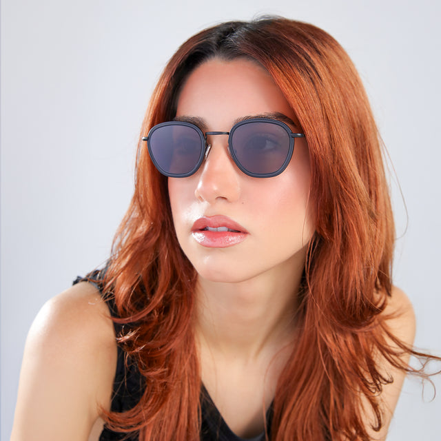 Another angle of woman with red hair in a black blouse wearing Prince Tate Sunglasses Matte Black with Grey Flat