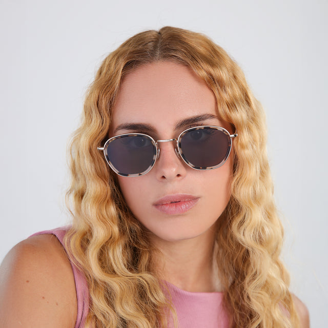 Another angle of woman with blond wavy hair in a pink blouse wearing Prince Tate Sunglasses White Tortoise/Gold with Grey Flat