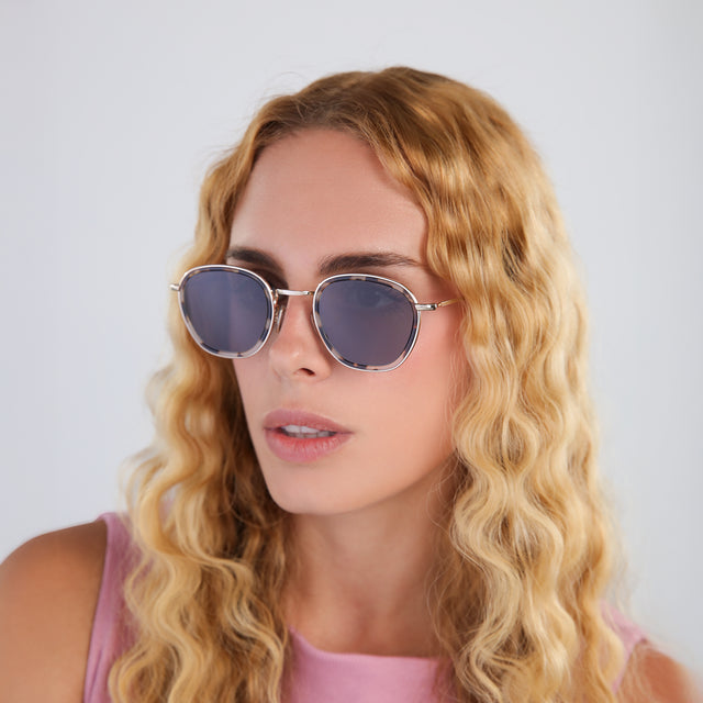 Woman with blond wavy hair in a pink blouse wearing Prince Tate Sunglasses White Tortoise/Gold with Grey Flat