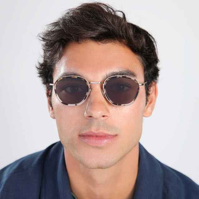 Another angle of man in a navy jacket Prince Tate Sunglasses front view in White Tortoise/Gold with Grey Flat