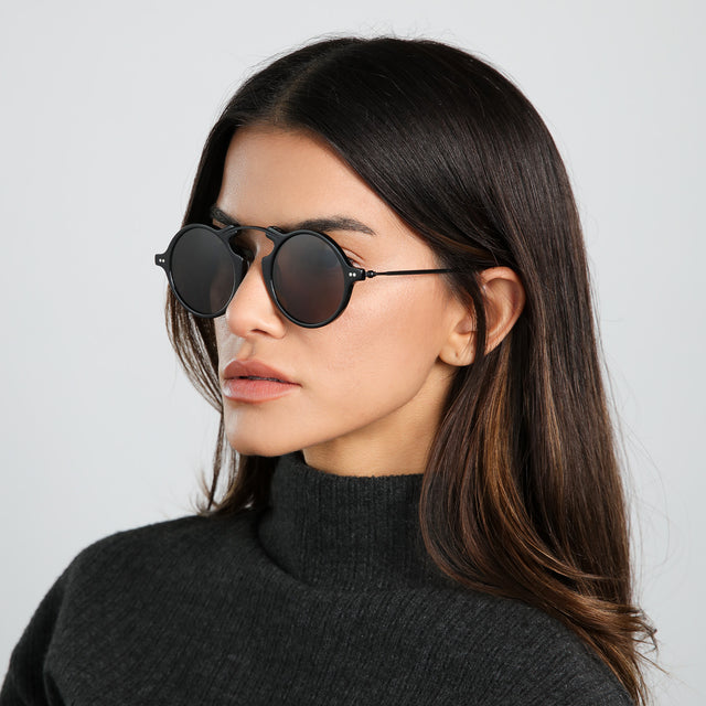 Angled view of brunette model wearing Roma II Sunglasses Black with Grey Flat