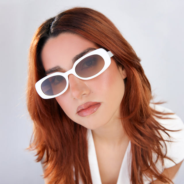 Close up angle of woman with red hair in a white blouse tilting her head Shirley 51 Sunglasses side view in White / Brown Gradient