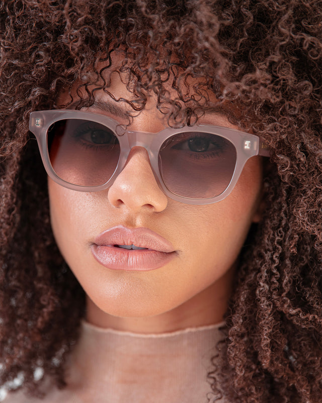 Brunette model with afro-curly hair wearing Vail Sunglasses Thistle with Brown Flat Gradient