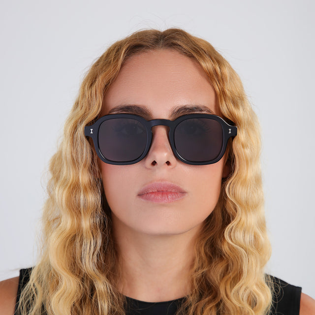 Another angle of blonde woman with curly hair wearing Washington Sunglasses Black with Grey Flat