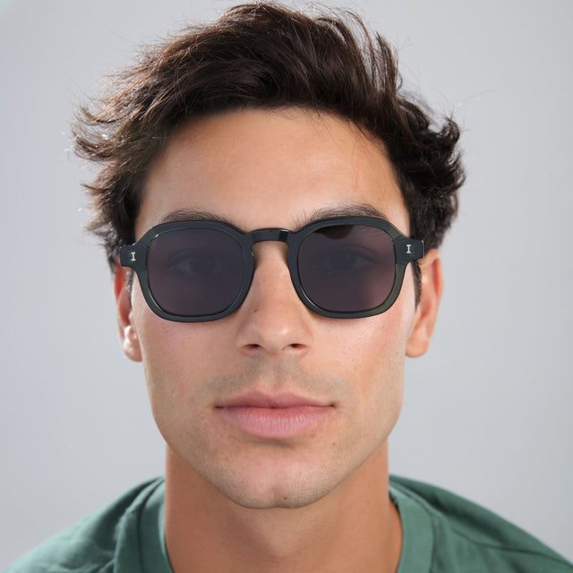 Man with brown hair in a green shirt wearing Washington Sunglasses Pine with Grey Flat