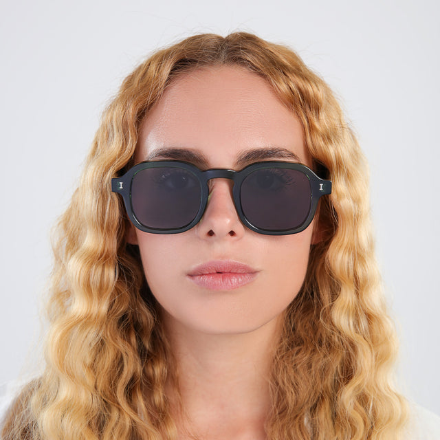 Another angle of blonde woman with curly hair wearing Washington Sunglasses Pine with Grey Flat