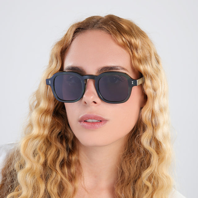 Blonde woman with curly hair wearing Washington Sunglasses Pine with Grey Flat