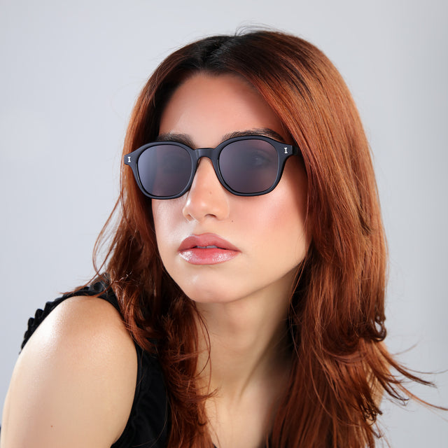 Woman with red hair in a black blouse wearing William Sunglasses Black with Grey