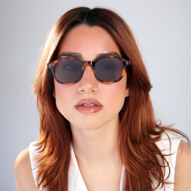 Woman with red hair in a white blouse wearing William Sunglasses Havana with Grey