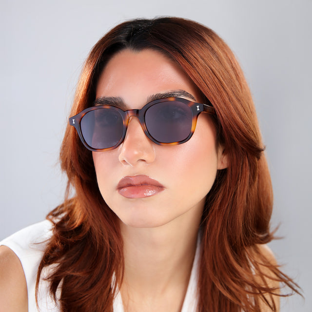 Close up of woman with red hair in a white blouse wearing William Sunglasses Havana with Grey