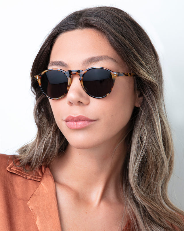 Brunette woman with highlights and a coral blouse wearing Capri Sunglasses Tortoise with Grey