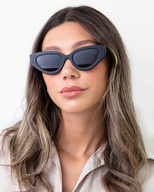 Brunette model in a silk blouse wearing Mary Lou Sunglasses Black with Grey Flat