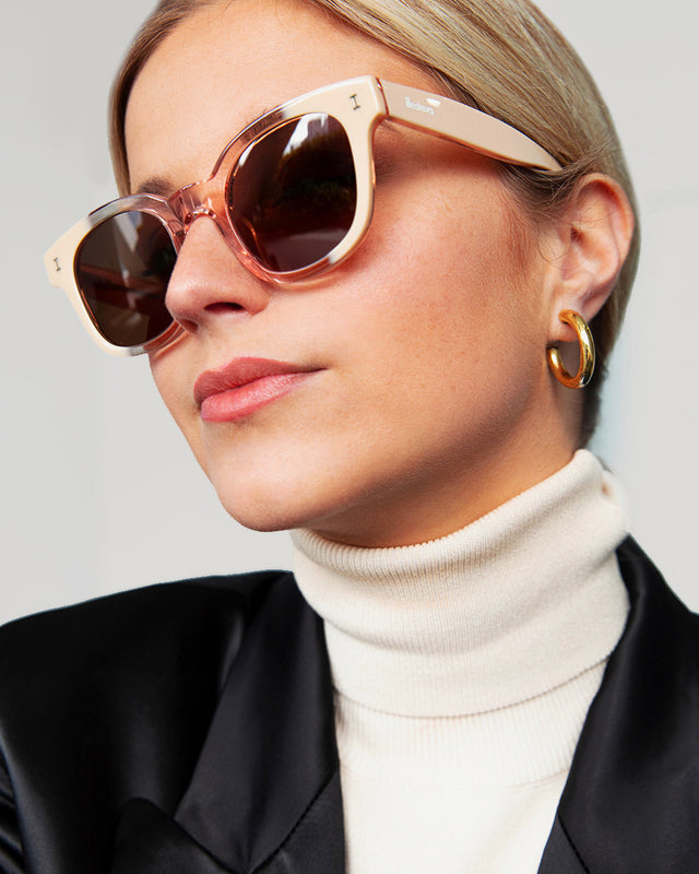 Blonde model with a low ponytail wearing Vail Sunglasses Strawberry Cream with Brown Flat