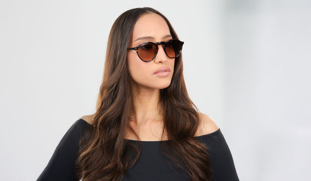 Woman in a black blouse wearing Capri Sunglasses in Flame with Brown lenses