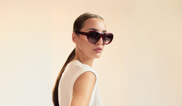 Woman in a cream blouse wearing Cynthia Rowley x illesteva Sunglasses in Mulberry