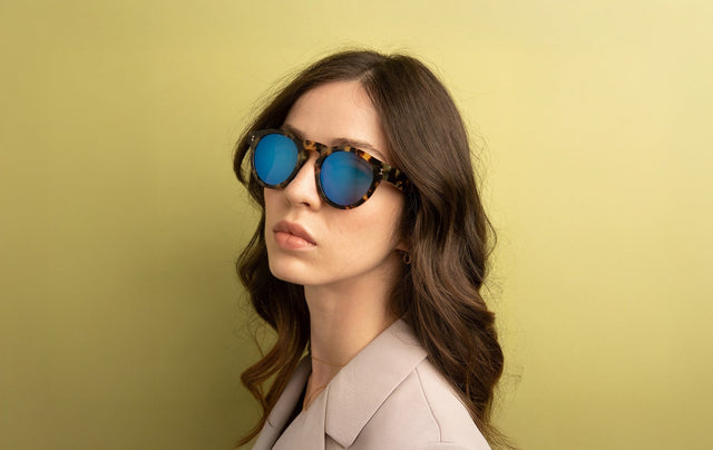 Woman in a beige blazer wearing the Leonard Sunglasses in Tortoise with Blue Mirror